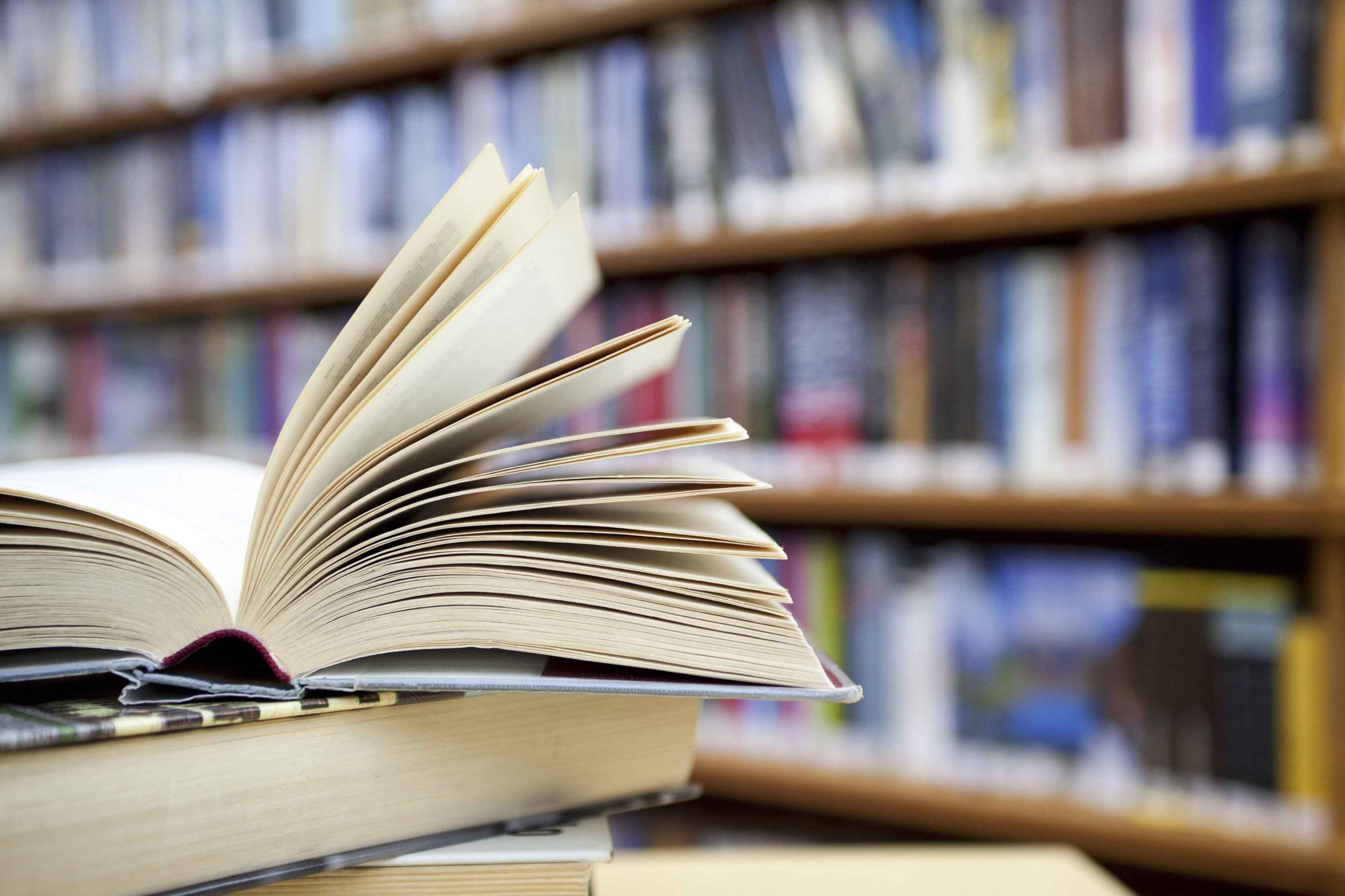 Picture of a book in front of library shelves.